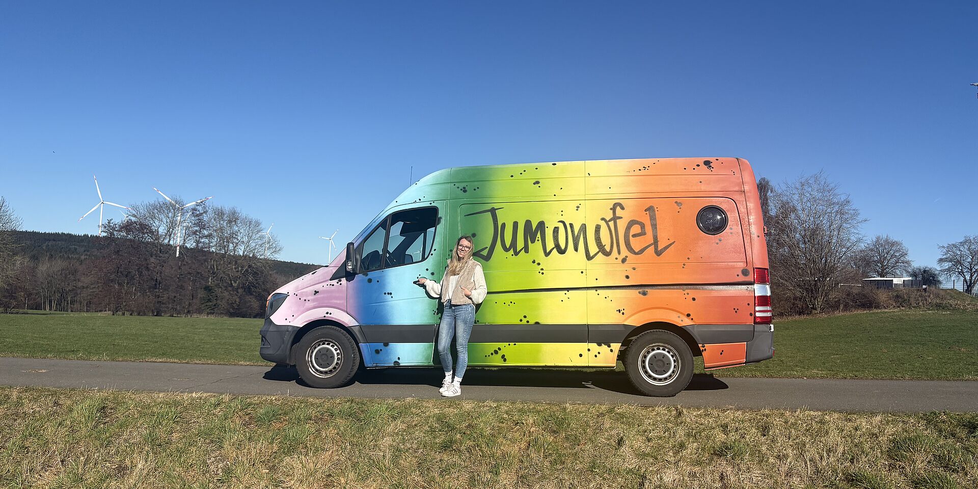 Eine Frau vor einem bunten Transporter