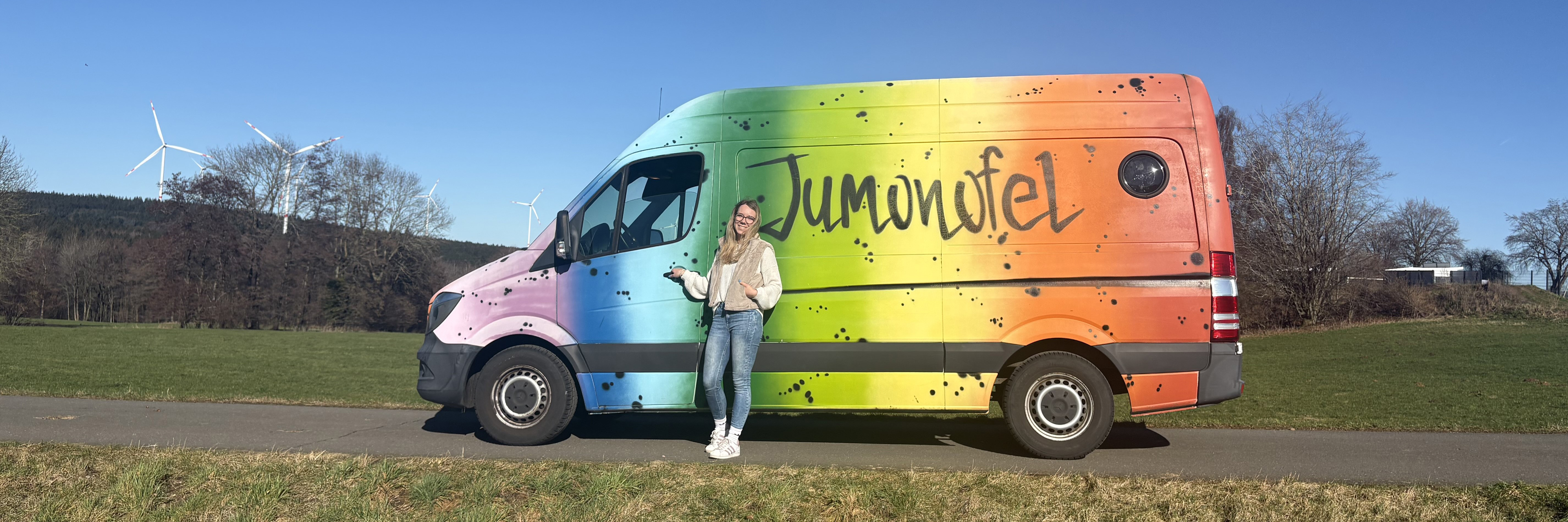 Junge Frau vor einem bunten Transporter 